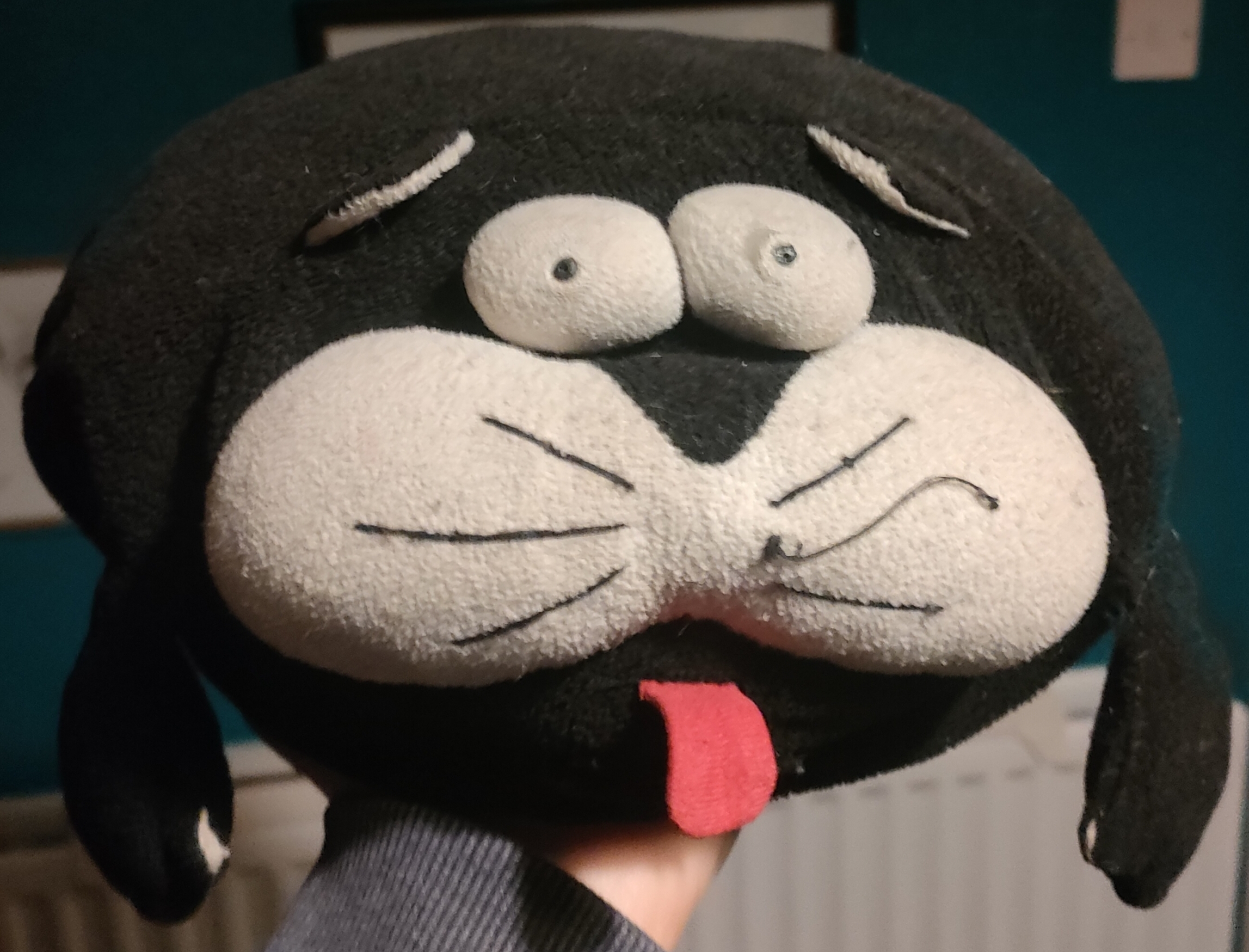 A picture of a round stuffed cat with its tongue sticking out.